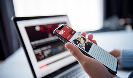 Photo of woman scrolling a news site on her phone