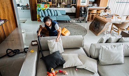 A housekeeper sweeps a couch