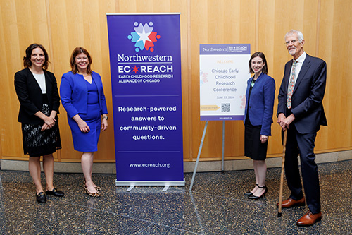 group of professors standing by a sign