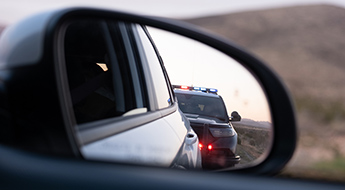 review window of car shows a police car pulling over the vehicle