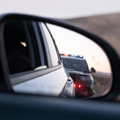 review window of car shows a police car pulling over the vehicle