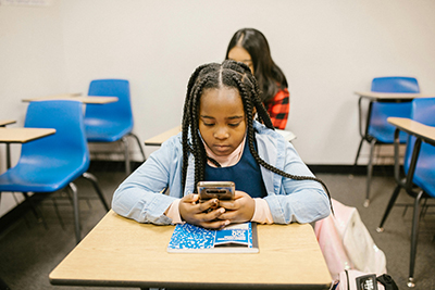 Black girl sitting at a desk with a phone
