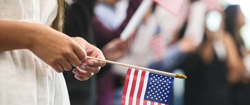 woman holding American flag at naturalization ceremony