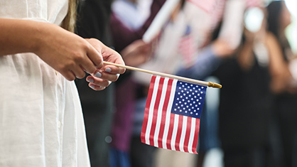 woman holding flag at naturalization ceremony