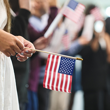 woman holding flag at naturalization ceremony