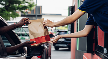 fast food worker handing order to customer in drive thru