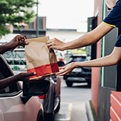 fast food worker handing order to customer in drive thru