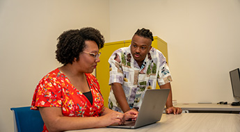Two researchers look at a laptop together